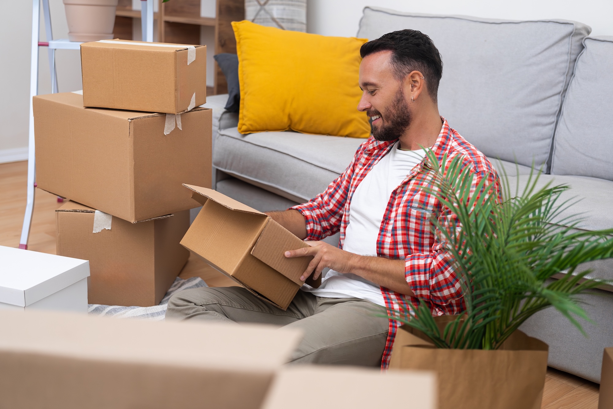 A young man unpacks boxes on his moving day, finding a moment of calm on the sofa in his new home, symbolizing the essence of relocation