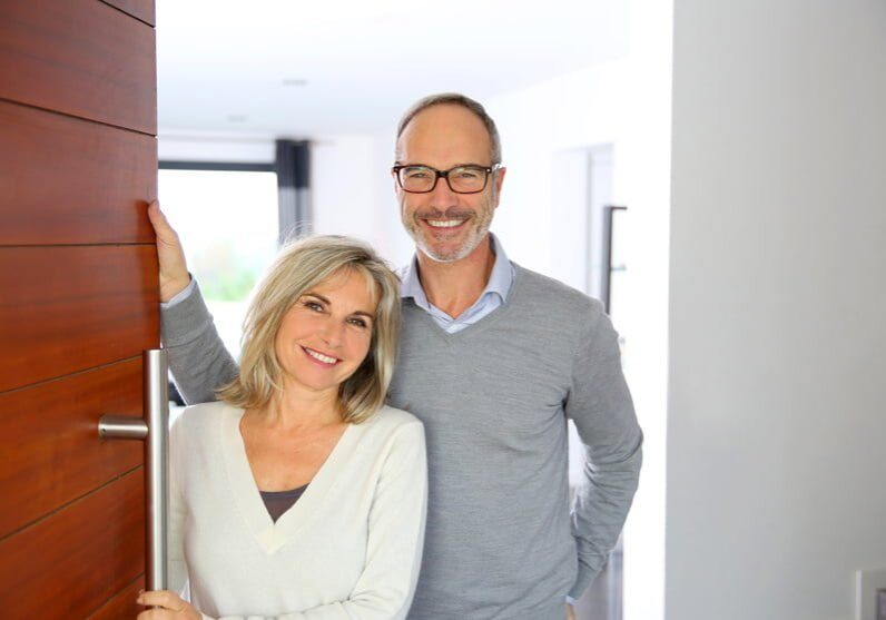 Senior couple welcoming people to enter home
